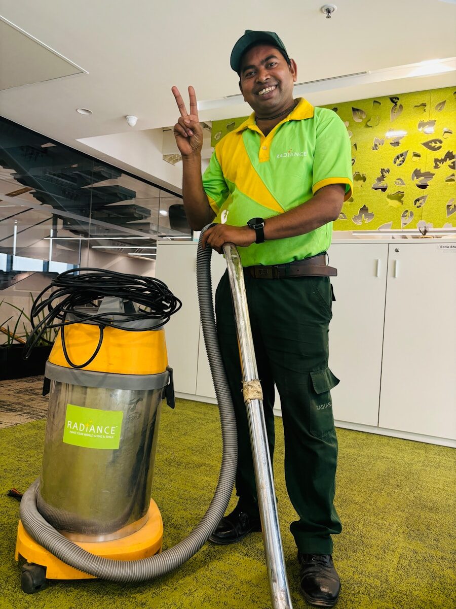 A man in a green shirt is holding a vacuum